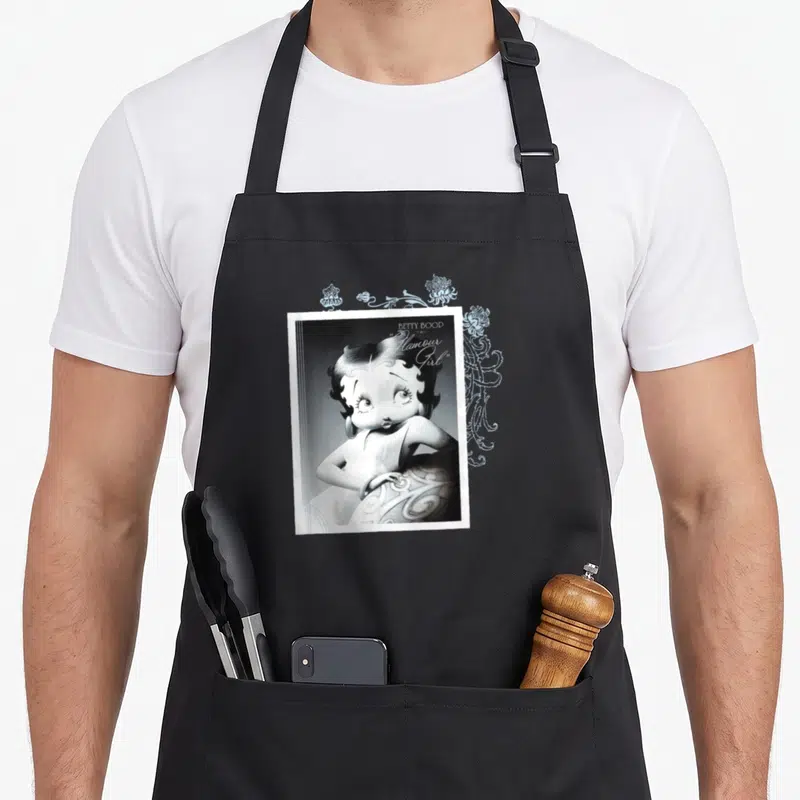 Tablier de cuisine noir avec illustration vintage de Betty Boop et texte Humour Girl en typographie cursive.