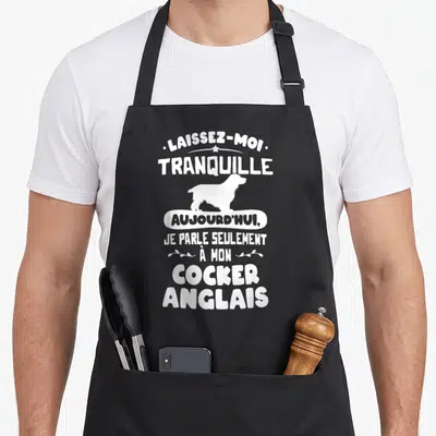 Tablier de cuisine noir avec silhouette blanche de Cocker Anglais et texte humoristique en typographie épaisse.