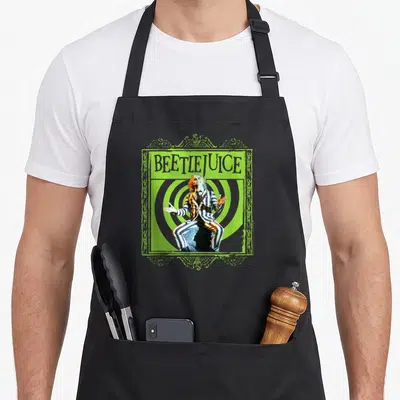 Tablier de cuisine noir avec illustration Beetlejuice en costume rayé sur fond de spirales vertes.