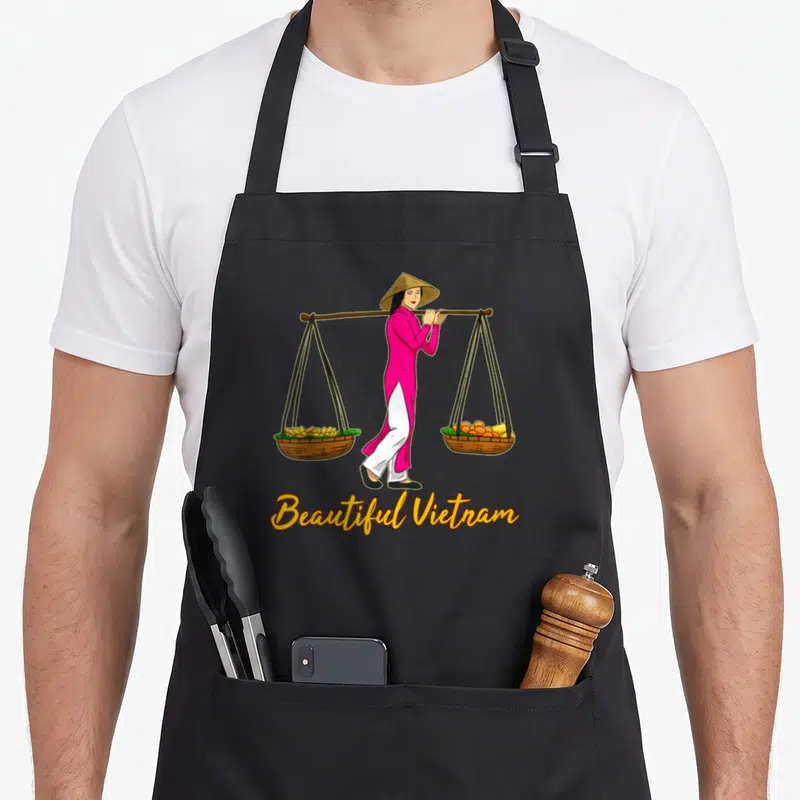 Tablier de cuisine noir avec une femme en ao dai portant deux paniers de fruits et la mention « Belle Vietnam » en dessous.