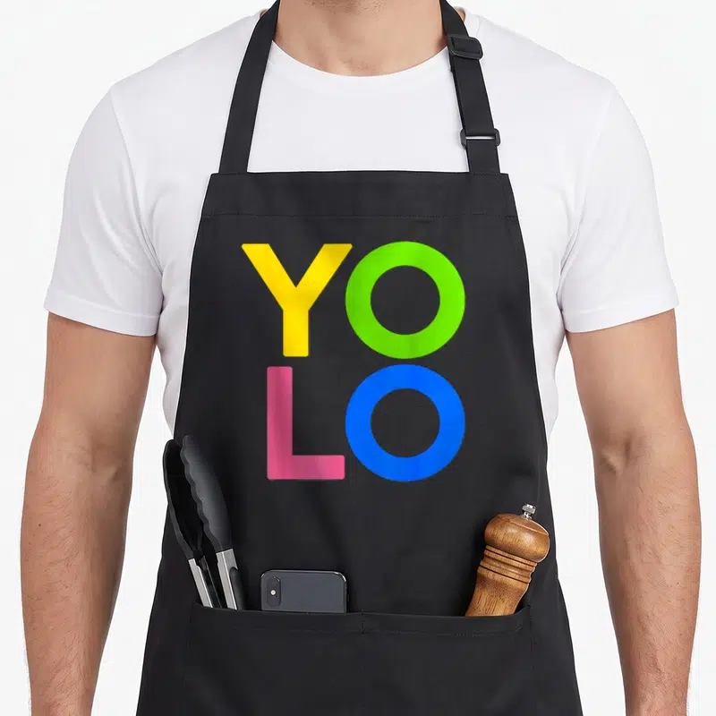 Tablier de cuisine noir avec l'acronyme YOLO imprimé en jaune, vert, rose et bleu vif.