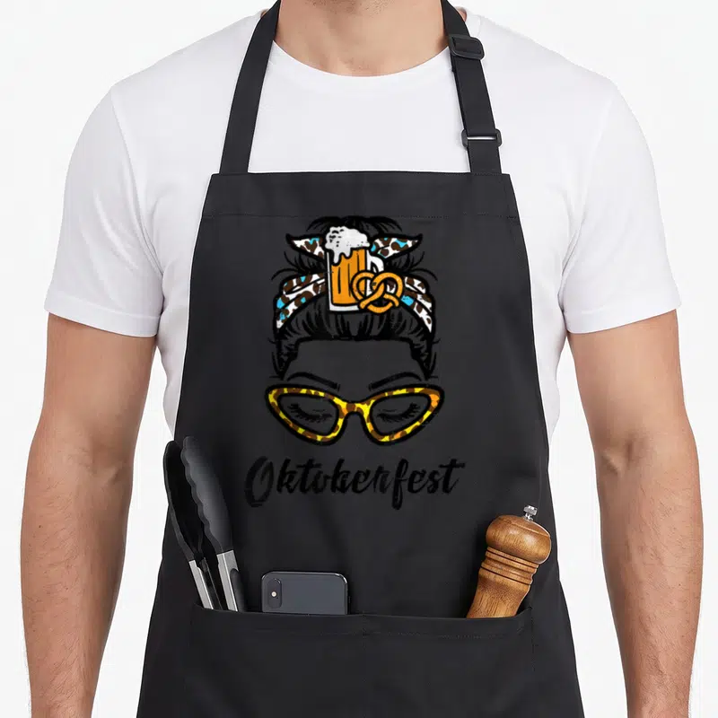 Tablier de cuisine noir avec illustration d'une femme aux lunettes léopard et un chapeau orné de bière et pretzel.