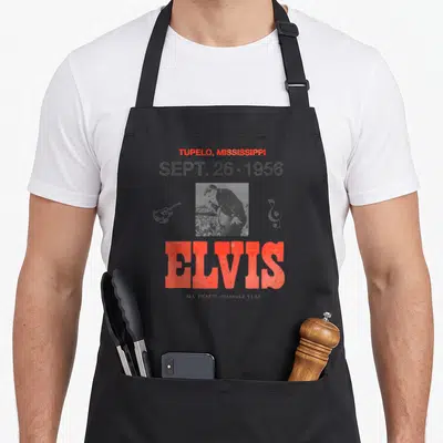 Tablier de cuisine noir avec affiche concert Elvis Tupelo Mississippi 1956 en rouge et noir.
