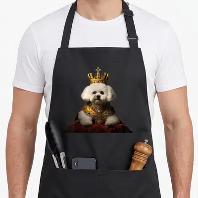 Tablier de cuisine noir avec un bichon frisé portant une couronne et une cape royale.