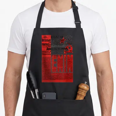 Tablier de cuisine noir avec reproduction du journal Izvestia en rouge et texte en alphabet cyrillique.