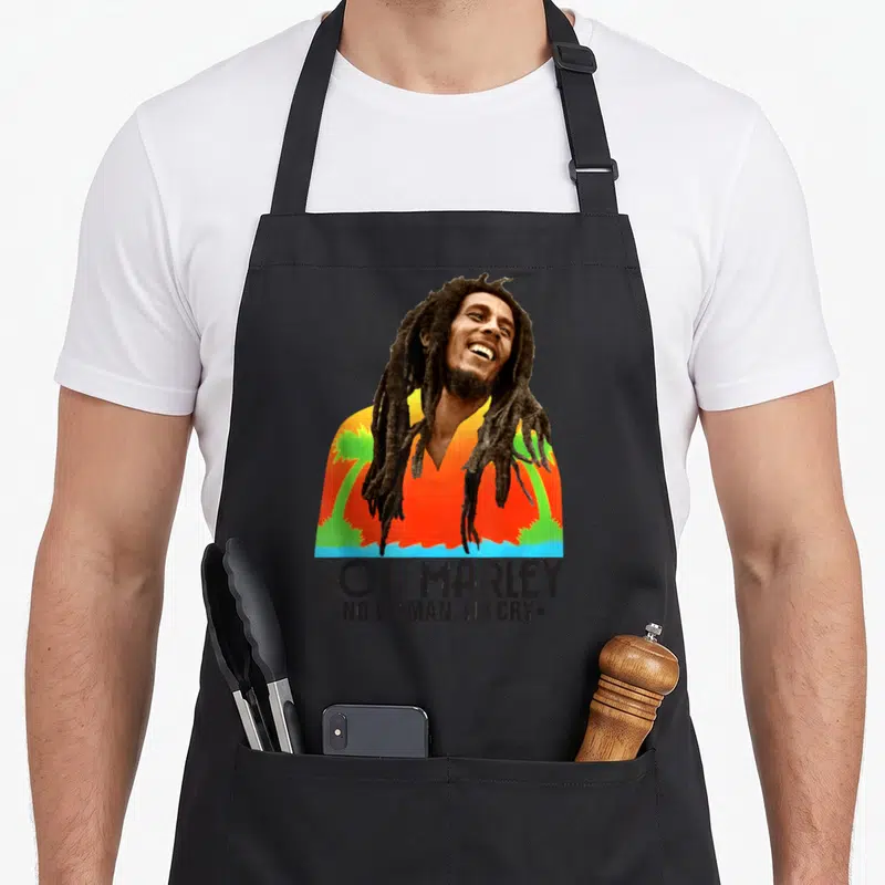 Tablier de cuisine noir avec portrait coloré de Bob Marley et texte No Woman No Cry en bas.