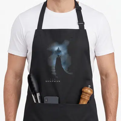 Tablier de cuisine noir avec une illustration bleutée d'un chemin menant à un château et le texte The Sandman.