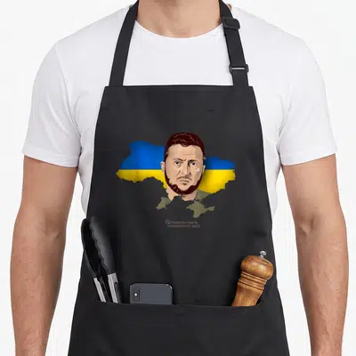 Tablier de cuisine noir avec portrait de Volodymyr Zelensky sur fond de carte Ukraine bleue et jaune.
