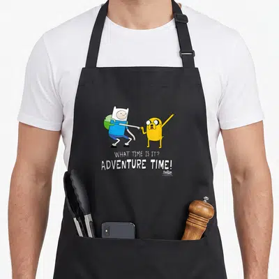 Tablier de cuisine noir avec Finn et Jake se faisant un poing et le texte What time is it Adventure Time imprimé en blanc.