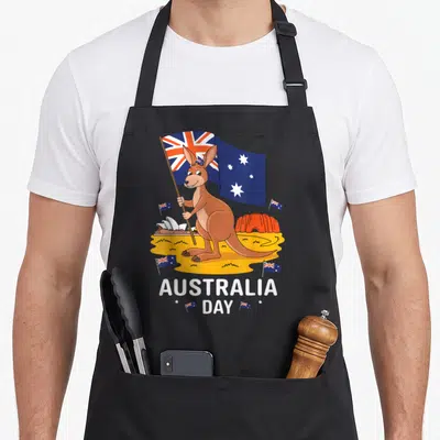 Tablier de cuisine noir avec un kangourou tenant le drapeau australien devant l'Opéra de Sydney et Uluru, texte Australia Day en bas.
