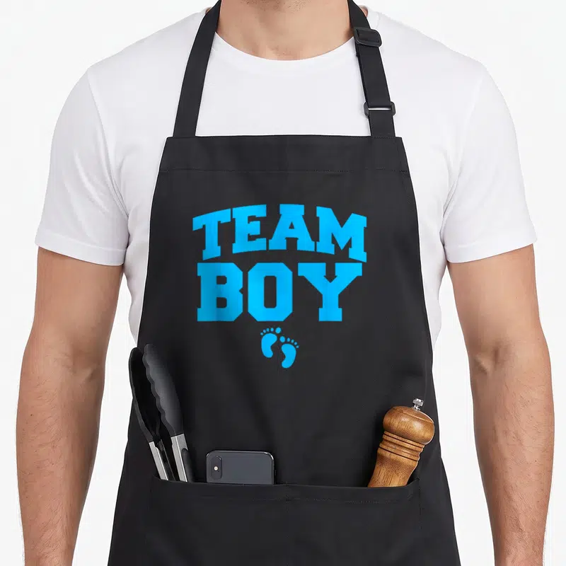 Tablier de cuisine noir avec l'inscription Team Boy et deux petites empreintes de pieds bleues en dessous du texte.