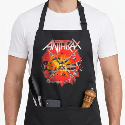 Tablier de cuisine noir avec logo Anthrax, crâne jaune et pistolets squelettiques en croix sur fond rouge éclaté.