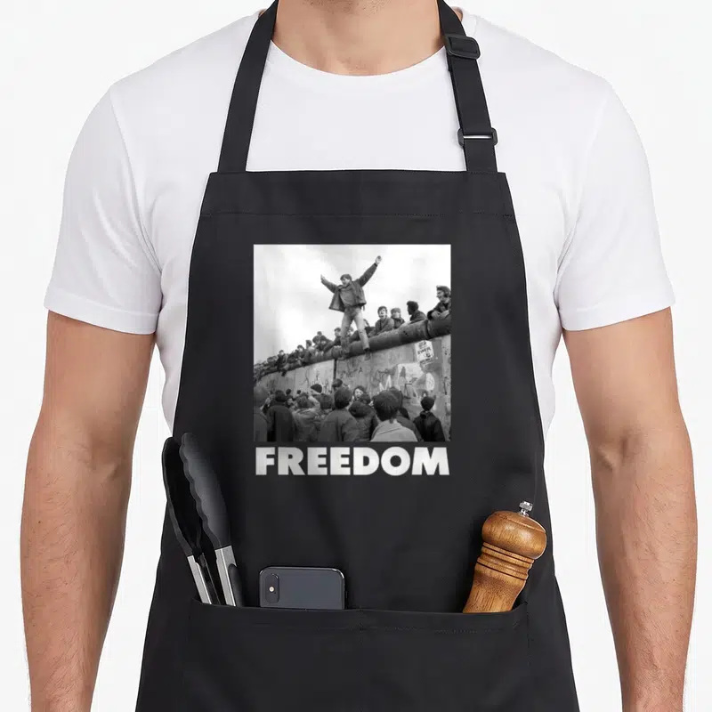 Tablier de cuisine noir avec photo historique sur un mur et le mot FREEDOT en bas.