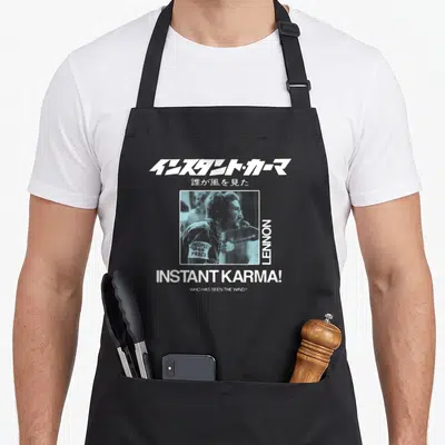 Tablier de cuisine noir avec illustration Instant Karma. John Lennon et texte en caractères japonais.