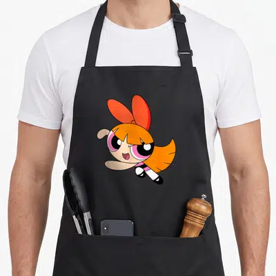 Tablier de cuisine noir avec Blossom des Powerpuff Girls aux cheveux orange et grand nœud rouge volant joyeusement.