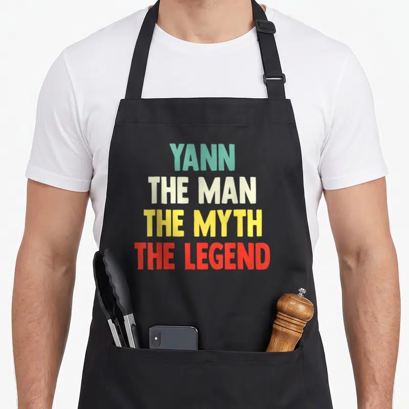 Tablier de cuisine noir avec le texte Yann The Man The Myth The Legend en lettres multicolores.