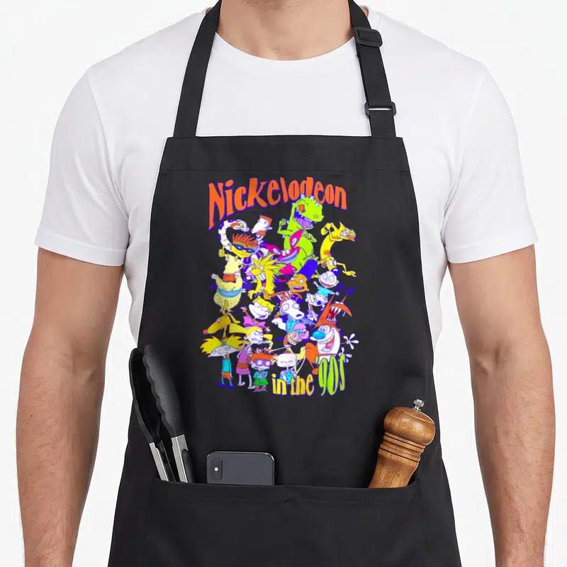 Tablier de cuisine noir avec une illustration colorée de personnages d'animation et le logo Nickelodeon in the 90s.