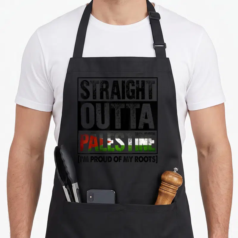 Tablier de cuisine noir avec inscriptionStraight Outta Palestine et drapeau coloré au centre du motif imprimé.