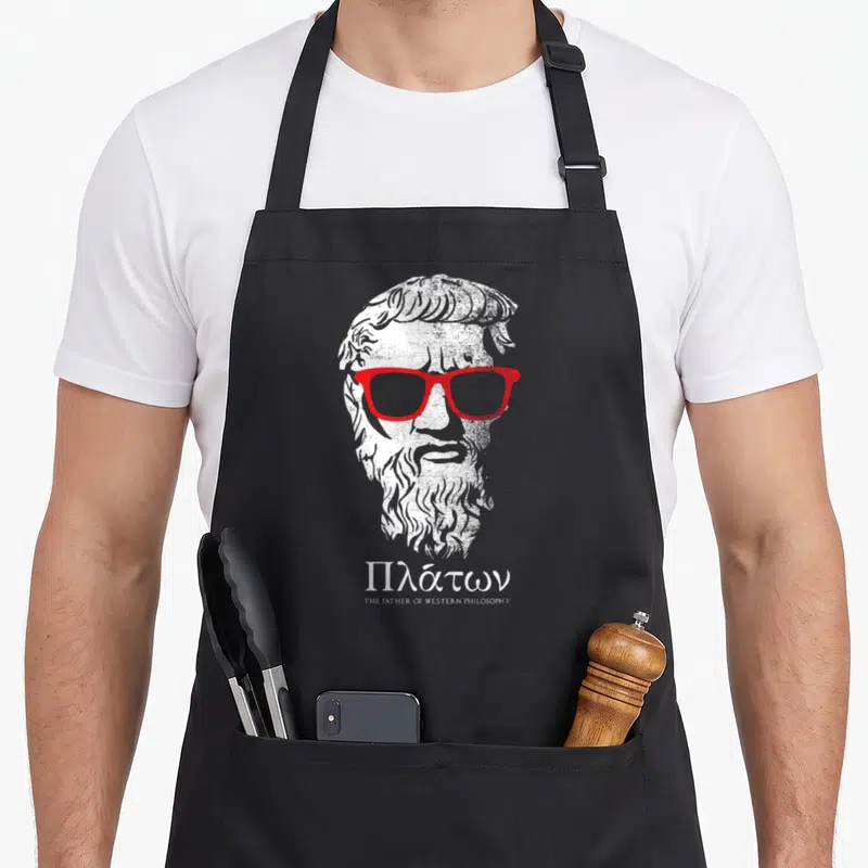 Tablier de cuisine noir avec buste de Platon portant des lunettes rouges et texte en grec.