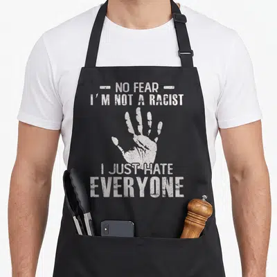 Tablier de cuisine noir avec inscription blanche NO FEAR I M NOT A RACIST I JUST HATE EVERYONE et trace de main.