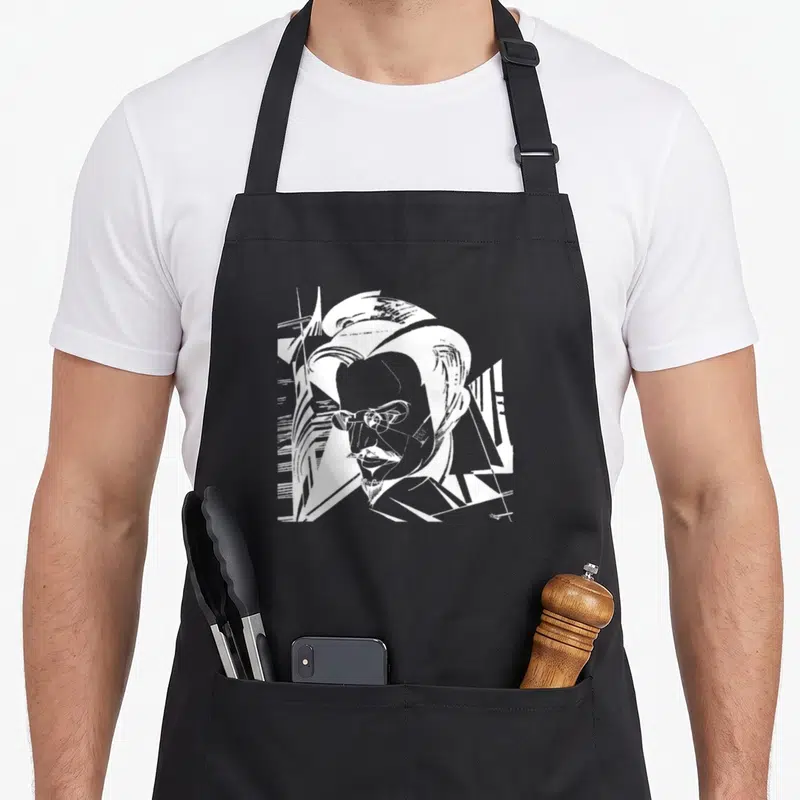 Tablier de cuisine noir avec portrait graphique blanc de Léon Trotsky aux traits anguleux et lunettes rondes.