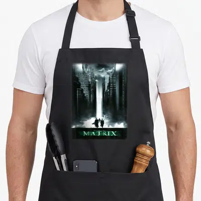 Tablier de cuisine noir avec illustration de la Simulated City et trois silhouettes devant le logo The Matrix.
