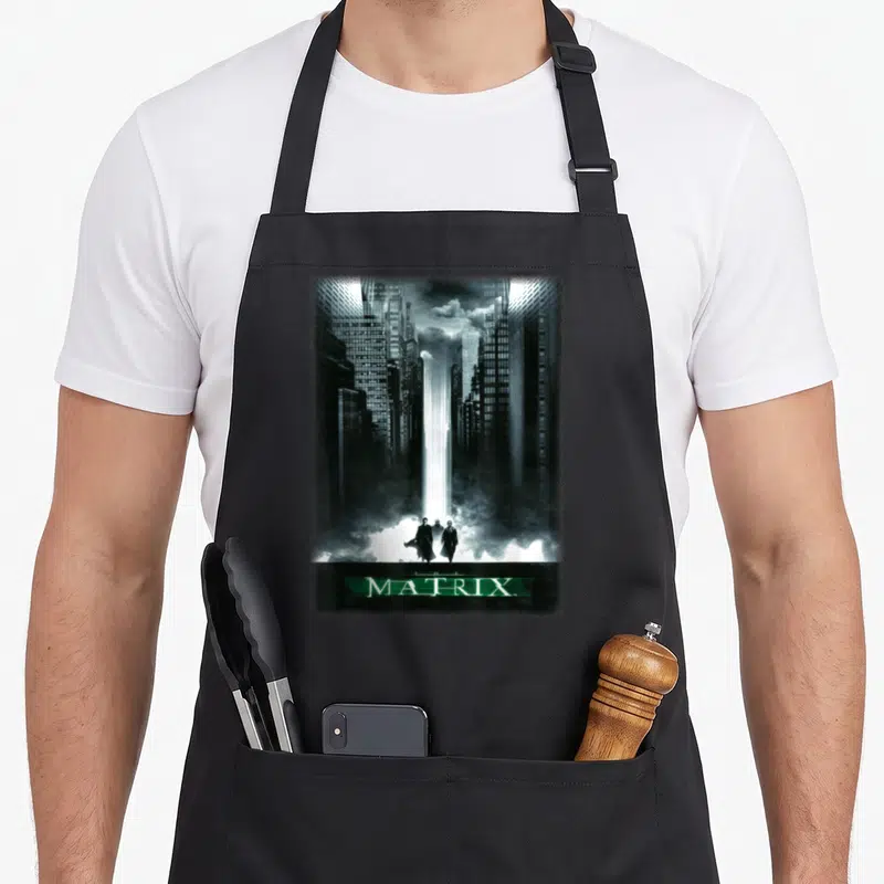 Tablier de cuisine noir avec illustration de la Simulated City et trois silhouettes devant le logo The Matrix.