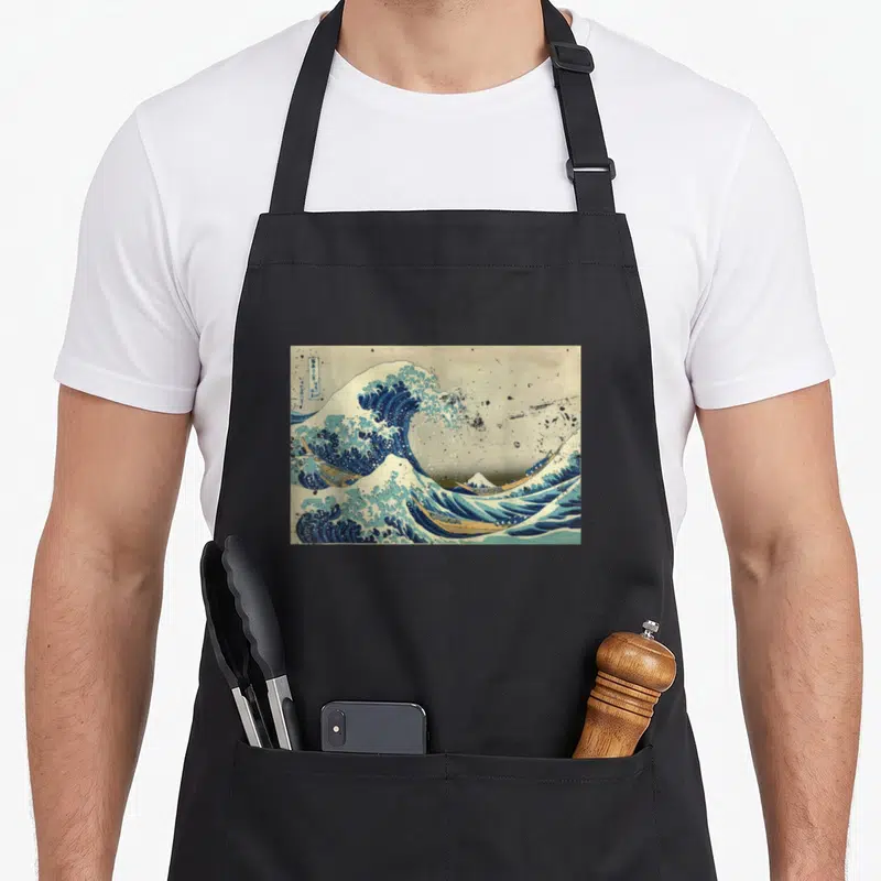 Tablier de cuisine noir avec reproduction de La grande vague au large de Kanagawa et bateaux en danger.