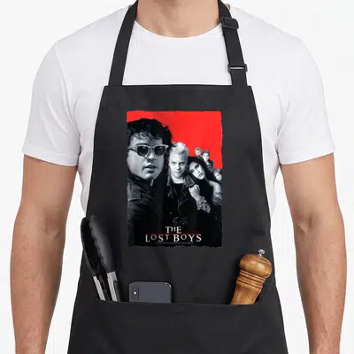 Tablier de cuisine noir avec le poster The Lost Boys en rouge et noir, bordure déchirée.
