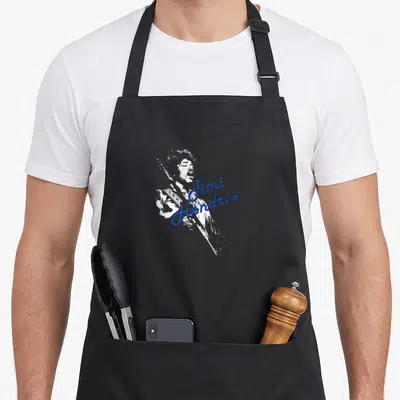 Tablier de cuisine noir avec silhouette blanche de Jimi Hendrix et signature bleue sur le devant.