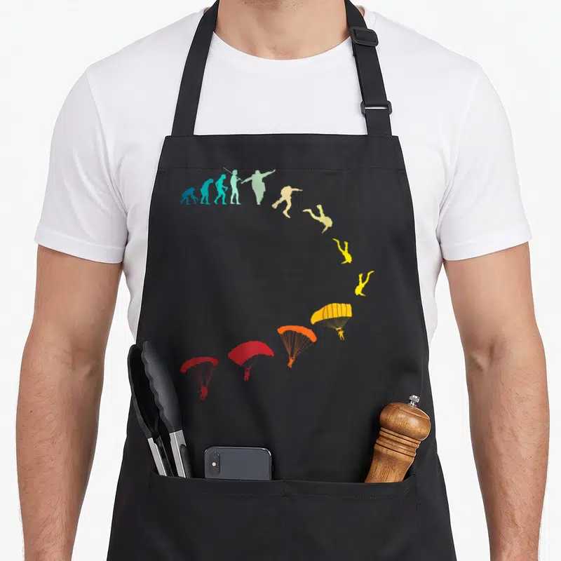 Tablier de cuisine noir avec illustration évolutive des silhouettes de parachutistes colorées en arc de cercle.
