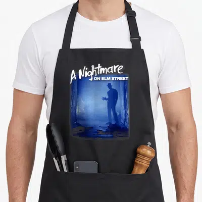 Tablier de cuisine noir avec une silhouette bleue de Freddy Krueger et le texte A Nightmare on Elm Street Freddy Is Waiting.