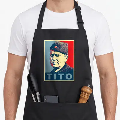 Tablier de cuisine noir avec portrait stylisé de Josip Broz Tito et le mot TITO en bas.