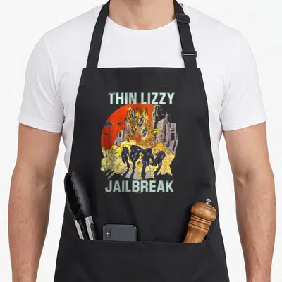 Tablier de cuisine noir avec illustration Jailbreak Thin Lizzy montrant une explosion et des silhouettes sur fond rouge.