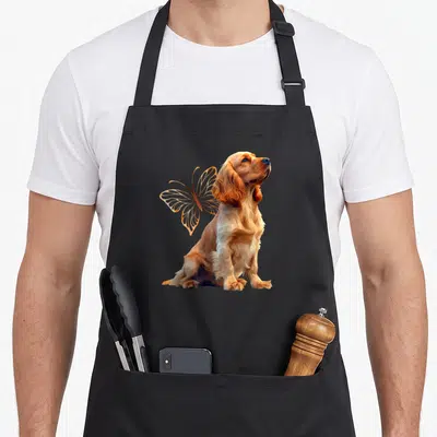 Tablier de cuisine noir avec illustration d'un Cocker anglais aux ailes de papillon dorées stylisées.