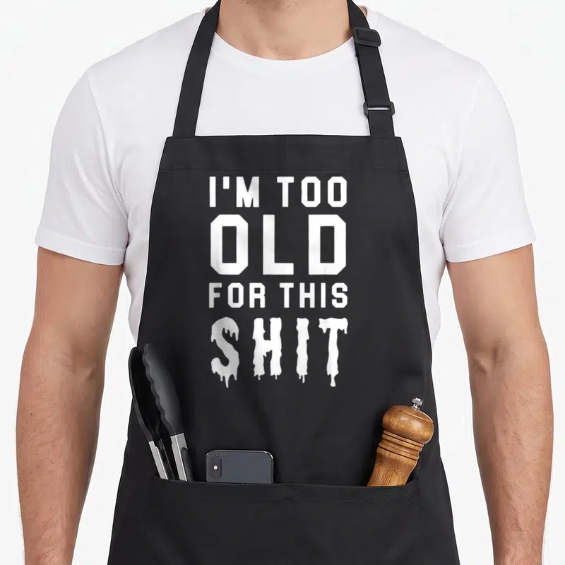 Tablier de cuisine noir avec inscription blanche « I'M TOO OLD FOR THIS SHIT » en typographie dripping.