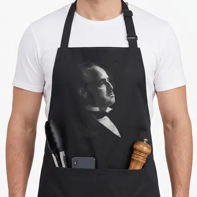 Tablier de cuisine noir avec portrait gravure de Vito Corleone et logo The Godfather en bas à gauche.