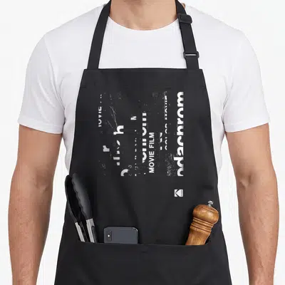 Tablier de cuisine noir avec motif graphique blanc évoquant le film Kodachrome et l'écriture MOVIE FILM.