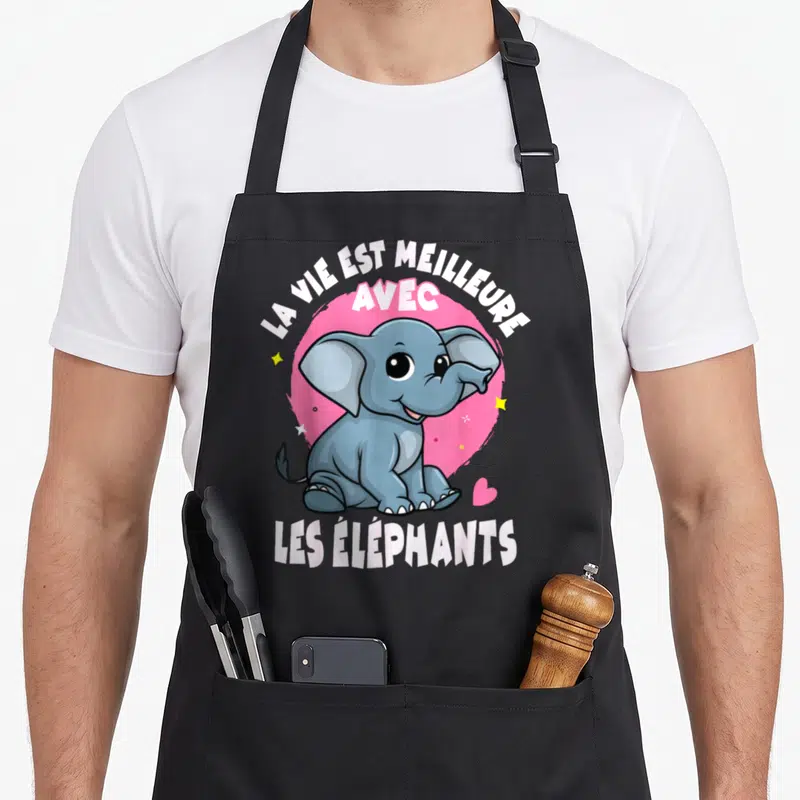 Tablier de cuisine noir avec un baby éléphant souriant sur fond rose et texte blanc.