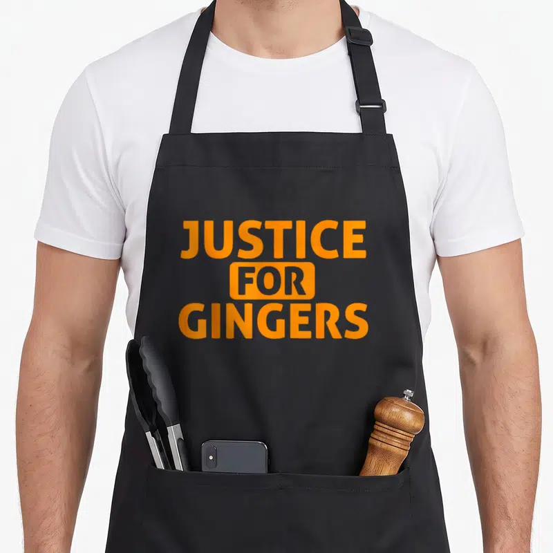 Tablier de cuisine noir avec inscription orange Justice for Gingers en typographie bold et stylisée.