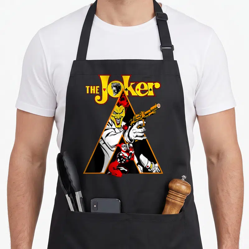Tablier de cuisine noir avec illustration triangulaire du Joker pointant un revolver.