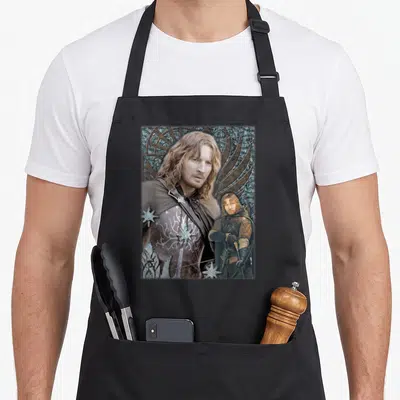 Tablier de cuisine noir avec le portrait de Faramir et ses étoiles argentées sur fond de motifs ornementaux sombres.