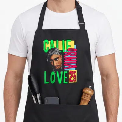 Tablier de cuisine noir avec portrait stylisé de 2PAC et texte California Love 2PAC en lettres vertes et roses.