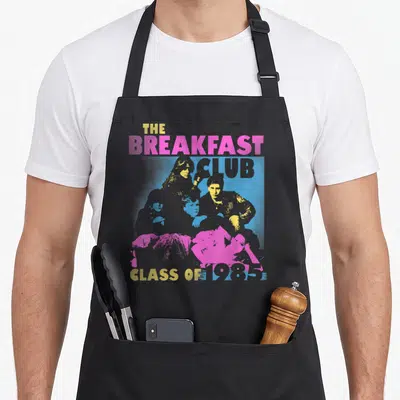 Tablier de cuisine noir avec le logo The Breakfast Club Class Of 1985 en stencil coloré.