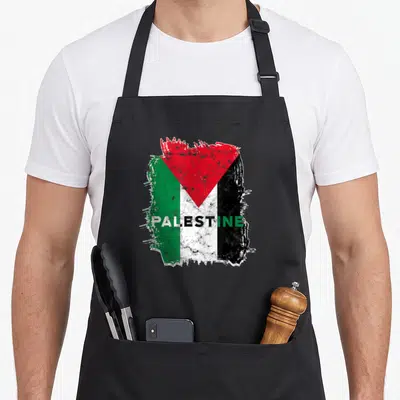 Tablier de cuisine noir avec drapeau Palestine stylisé et le mot PALESTINE en lettres capitales au centre du motif.