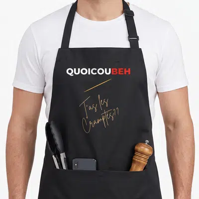 Tablier de cuisine noir avec le texte Quoicoubeh T'as les Cramp tes en lettres blanches rouges et oranges stylisées.