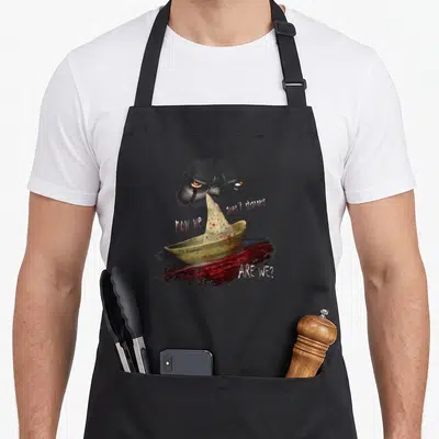 Tablier de cuisine noir avec bateau papier taché de rouge et regard menaçant au-dessus.