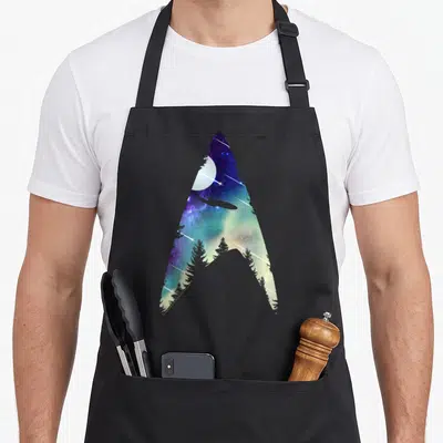 Tablier de cuisine noir avec insigne Starfleet stylisé espace et forêt
