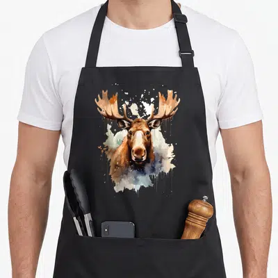 Tablier de cuisine noir avec tête d'élan en aquarelle et éclaboussures colorées sur fond neutre.