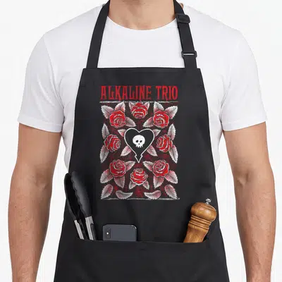 Tablier de cuisine noir avec logo Alkaline Trio, roses rouges et crâne blanc dans un cœur.